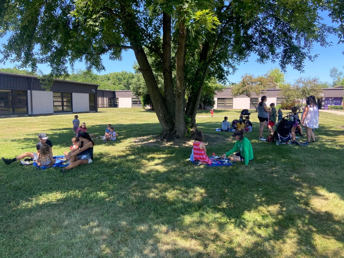 Children eating lunch under a tree